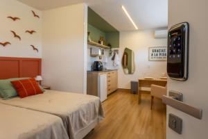 a bedroom with a bed and a desk and a kitchen at Studio Andorinhas in Brasília