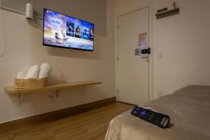 a bedroom with a tv on the wall and a remote control at Studio Andorinhas in Brasília