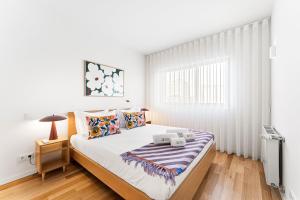 a white bedroom with a bed and a window at GuestReady - Menéres Apartments in Matosinhos +19 photos
