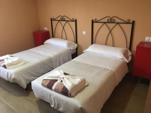 two beds in a hotel room with towels on them at Albergue La Perala in Bercianos del Real Camino