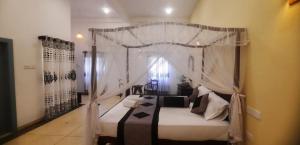 a bedroom with a white canopy bed with pillows at Coco Villa in Talpe