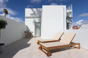 a patio with two lounge chairs on a white wall at Apartamentos Boutique Casco Histórico in Las Lagunas
