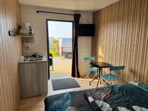 a bedroom with a bed and a table and a kitchen at Camping De Collignon in Cherbourg en Cotentin