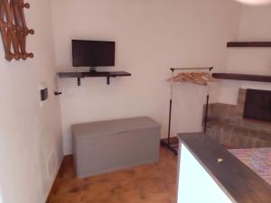 ein Zimmer mit einem Fernseher, einem Bett und einem Tisch in der Unterkunft Le 5 querce in Nettuno