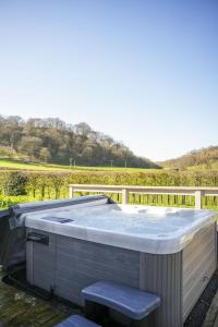 a hot tub on a deck with a vineyard at Oak Lodge in Knighton