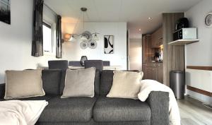 a living room with a gray couch and a kitchen at Chalet 6 Wellenruh in Westerland