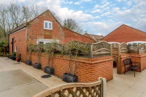 a brick wall with a fence with potted plants on it at 5 Bed in Chedgrave oc-twcg in Chedgrave