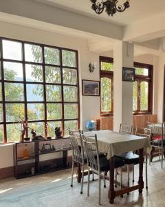 a dining room with a table and chairs and windows at The Di-Lac Retreat in Gangtok