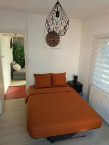 a bedroom with a large orange bed and a chandelier at Small townhouse in Clermont-Ferrand