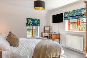 a bedroom with a bed and a desk and two windows at 4 Bed in Burrowbridge oc-o33020 in Athelney +26 photos