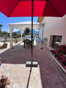 a red umbrella sitting on top of a patio at La Cocotte Rousse, ses Petits Déjeuners et sa Table in Parves +5 photos