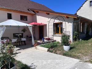 a house with a patio with a table and an umbrella at La Cocotte Rousse, ses Petits Déjeuners et sa Table in Parves