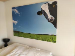 a picture of a cow on the wall of a bedroom at Havenkantoortje in Woudsend