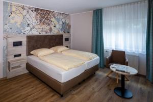 een slaapkamer met een bed, een stoel en een tafel bij Hotel-Restaurant Dimmer - Mullerthal in Wallendorf pont