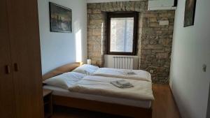 a bed in a room with a brick wall at Rooms Svalina in Grožnjan