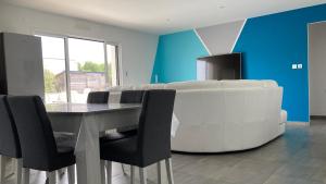a living room with a white couch and a table and chairs at Villa turquoise - piscine privée, terrasse bois in Saint-Jean-de-Monts