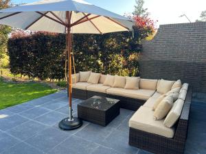 a patio with a couch and an umbrella at Maison François in Oostkamp