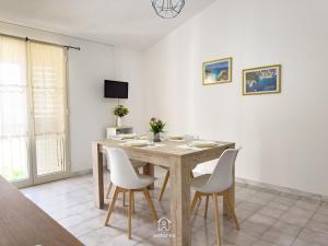 a dining room with a wooden table and white chairs at Residenza Centrale in Villasimius