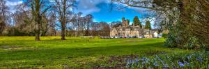 an old house in a park with trees and flowers at Mansion House Hotel in Elgin