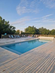 a swimming pool with chairs and a wooden deck at La clef des champs in Meillac