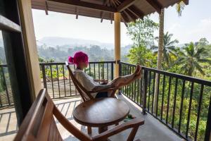 a woman sitting in a rocking chair on a balcony at Rainforest Hide View in Deniyaya