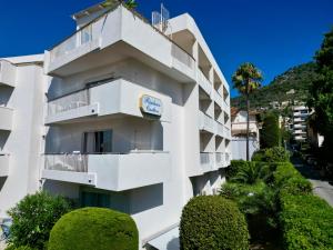 a white building with bushes in front of it at Résidence Carlton - Rénovée avec Piscine in Beaulieu-sur-Mer
