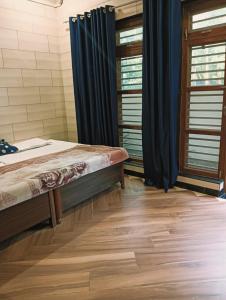 a bedroom with a bed with blue curtains and wooden floors at Kirpalu haridham hotel in Vrindāvan