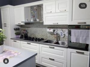 a kitchen with white cabinets and a sink at Acquamarina Luxury House in Budoni +2 photos