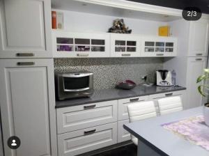 a kitchen with white cabinets and a microwave at Acquamarina Luxury House in Budoni
