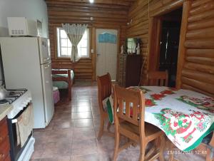 a kitchen and dining room with a table and a refrigerator at Cabañas la calma in Concordia