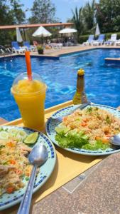two plates of food and a drink on a table near a pool at Poonsap Resort in Ko Lanta