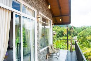 an outdoor balcony with glass doors and a bench at MulBerry Villa in Kandy