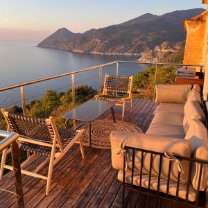 a balcony with a couch and chairs and the ocean at Large period house with panoramic view in Canari