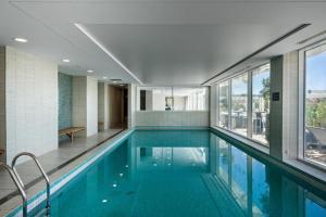 a large swimming pool in a building with windows at Golden Tulip Marseille Euromed in Marseille