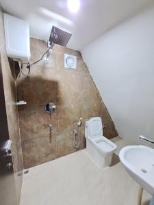 a bathroom with a toilet and a shower and a sink at Mung Kham Stays in Jorhat