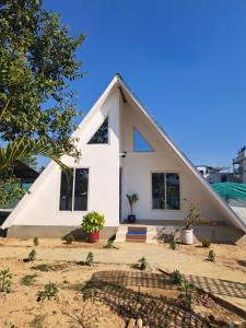 a white house with a triangular roof at Mung Kham Stays in Jorhat