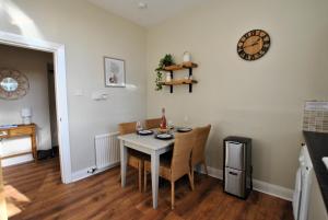 a dining room with a table and chairs and a clock at Kirkmay House Apartment in Crail