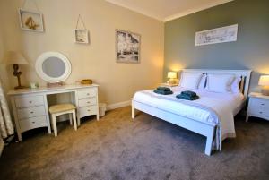 a bedroom with a bed and a vanity and a mirror at Kirkmay House Apartment in Crail
