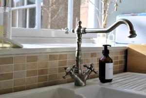 a bottle of soap sitting next to a kitchen sink at Kirkmay House Apartment in Crail +25 photos