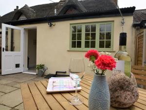 a table with a bottle of wine and a vase with flowers at 1 Bed in Sherborne oc-51018 in Bradford Abbas