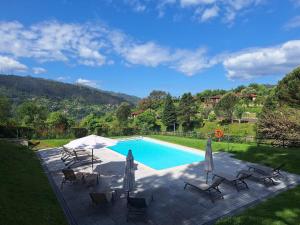 a swimming pool with chairs and umbrellas in a yard at Villas do Agrinho - Gerês in Geres
