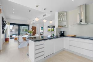 a kitchen with white cabinets and a living room at Villa Sol in Orihuela Costa