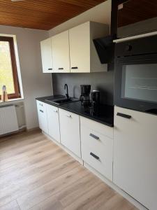 a kitchen with white cabinets and a flat screen tv at Ferienwohnung Obernkirchen in Obernkirchen