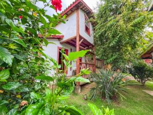a small white house with red windows in a garden at Pousada Villa Cachoeira in Carrancas