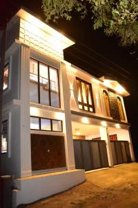 a white house with lit up windows at night at Everfreshhighviewcottage in Ooty +17 photos