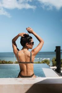 a woman in a bikini sitting next to a swimming pool at Beach House Costa Yucatan by Trobbu Collection in Xtampú +55 photos