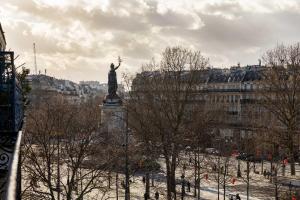 eine Statue einer Person auf einem Sockel in einer Stadt in der Unterkunft Korner République in Paris
