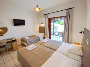 a hotel room with two beds and a desk and a television at Villa Anna Maria in Agia Paraskevi