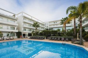 a swimming pool in front of a building with palm trees at Hotel Sun Palace Albir & Spa in Albir