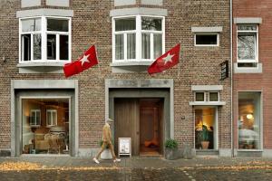 a man walking in front of a brick building with canadian flags at Townhouse Apartments Maastricht in Maastricht